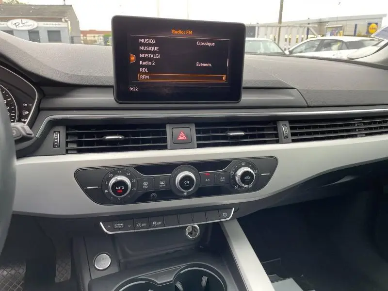 Tableau de bord de l'Audi A4 Avant 2019 avec écran central affichant les radios FM et commandes de climatisation en vue frontale.