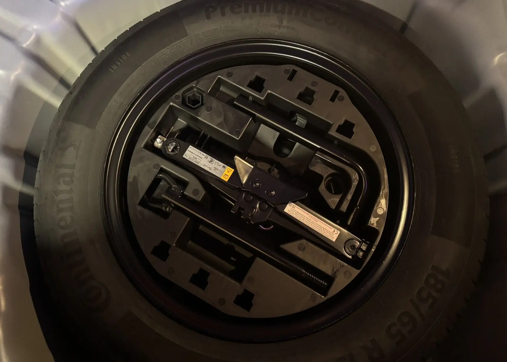 Gros plan sur la roue de secours noire et ses outils de bord dans le coffre d'une Renault Clio Bleu Iron 2024.