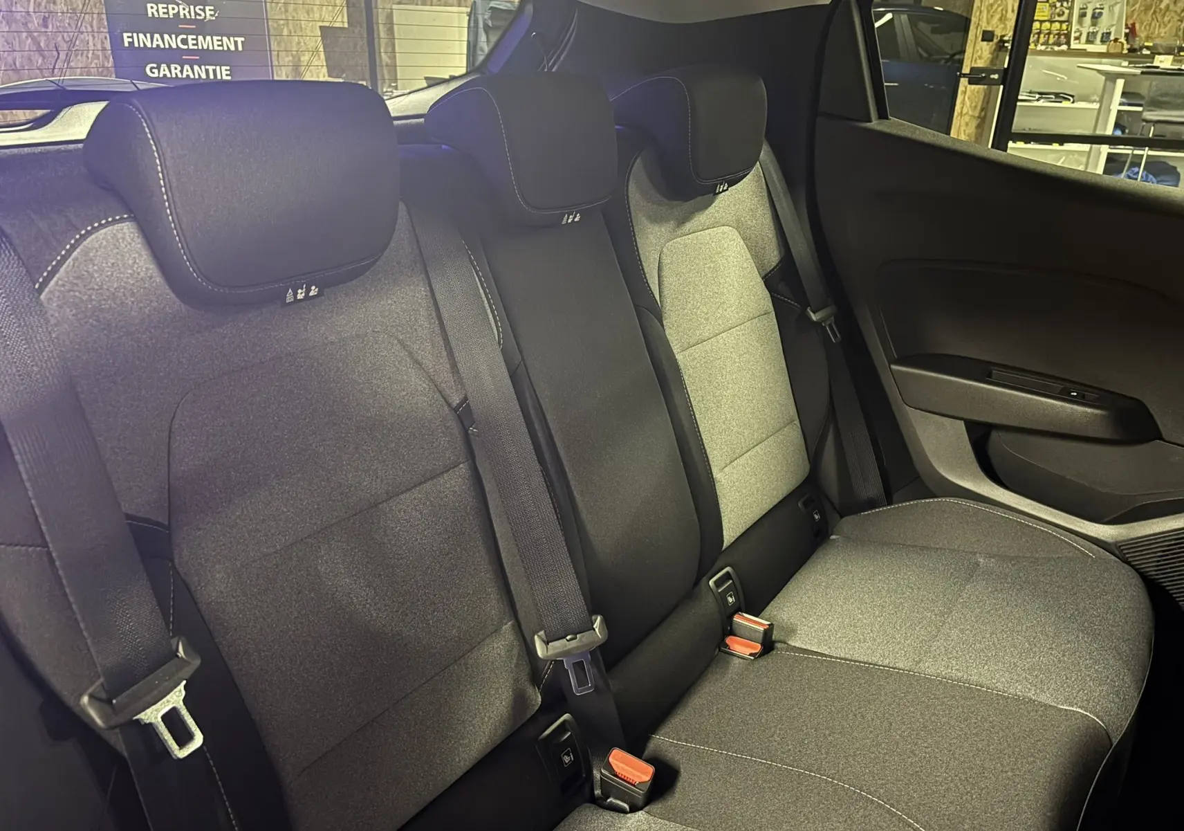 Vue intérieure sur les sièges arrière gris noir de la Renault Clio 2024, avec ceintures de sécurité et appuie-têtes visibles.