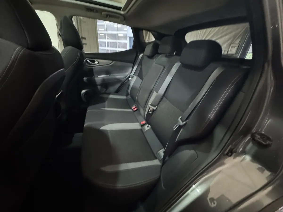 Vue intérieure côté droit sur la banquette arrière noire du Nissan Qashqai gris foncé, avec ceintures de sécurité visibles.