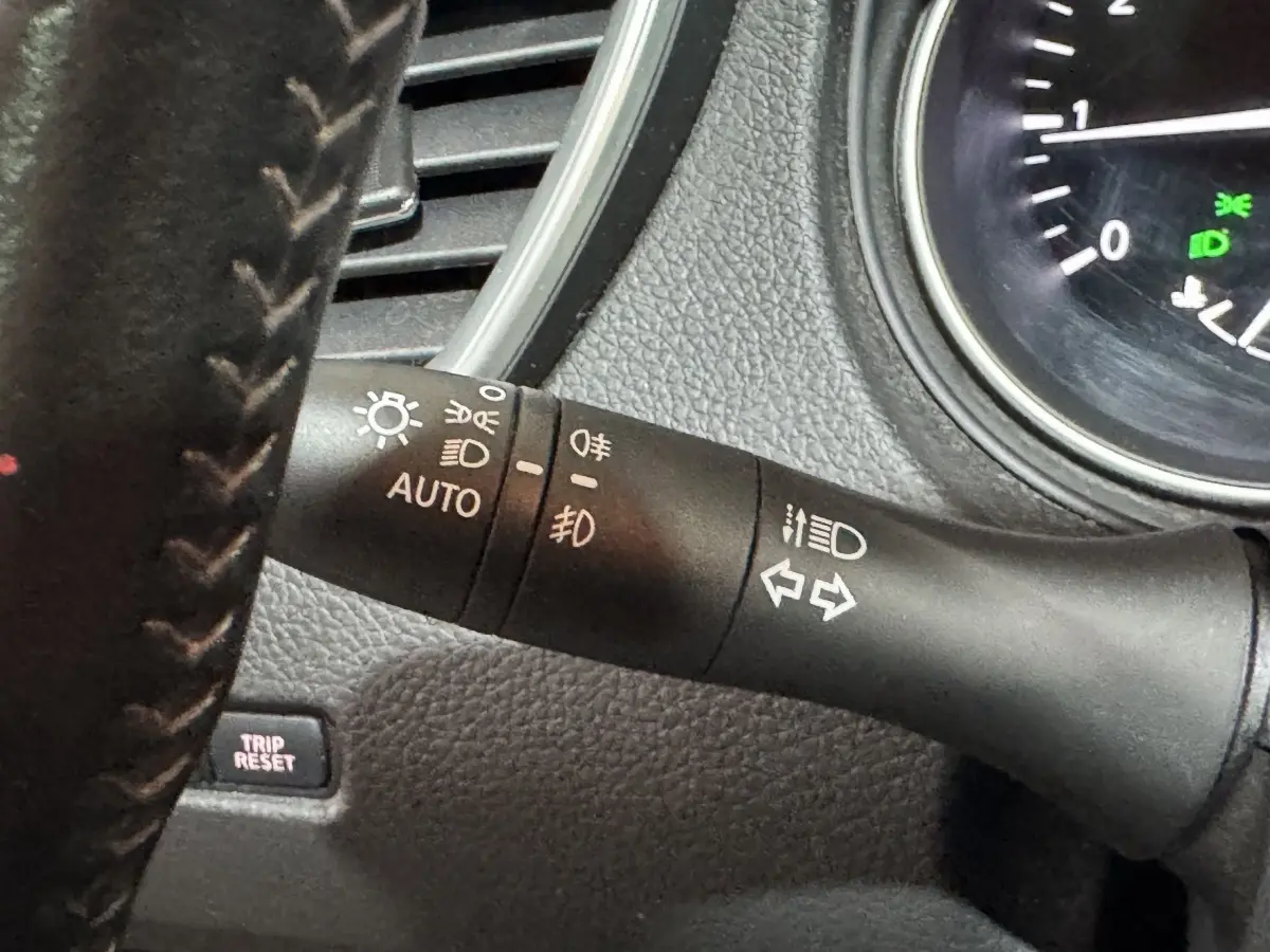 Gros plan sur la manette de commande des phares et clignotants du Nissan Qashqai gris foncé, intérieur tableau de bord.