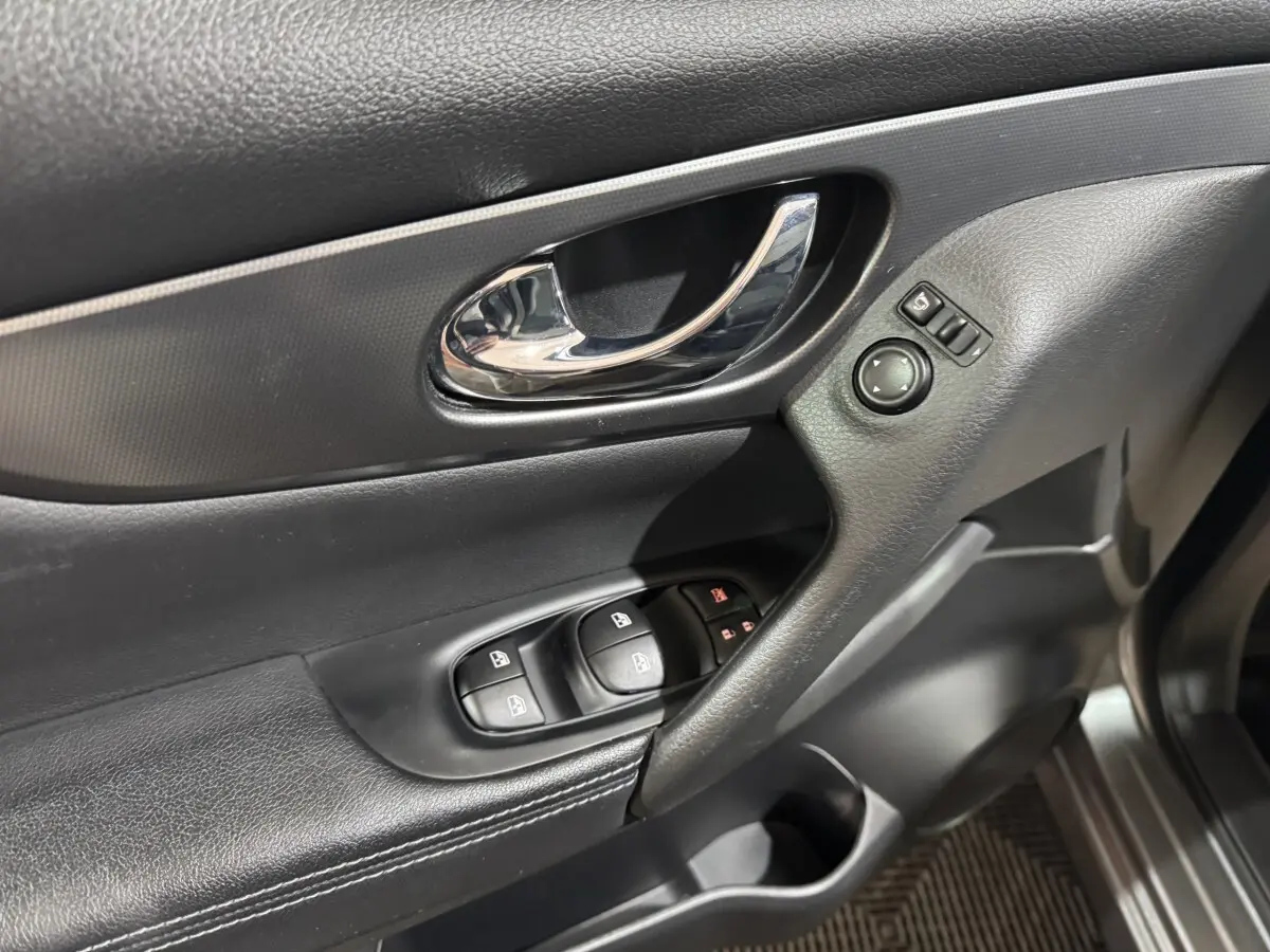 Gros plan sur la porte avant gauche du Nissan Qashqai gris foncé, avec commandes vitres et rétroviseurs.