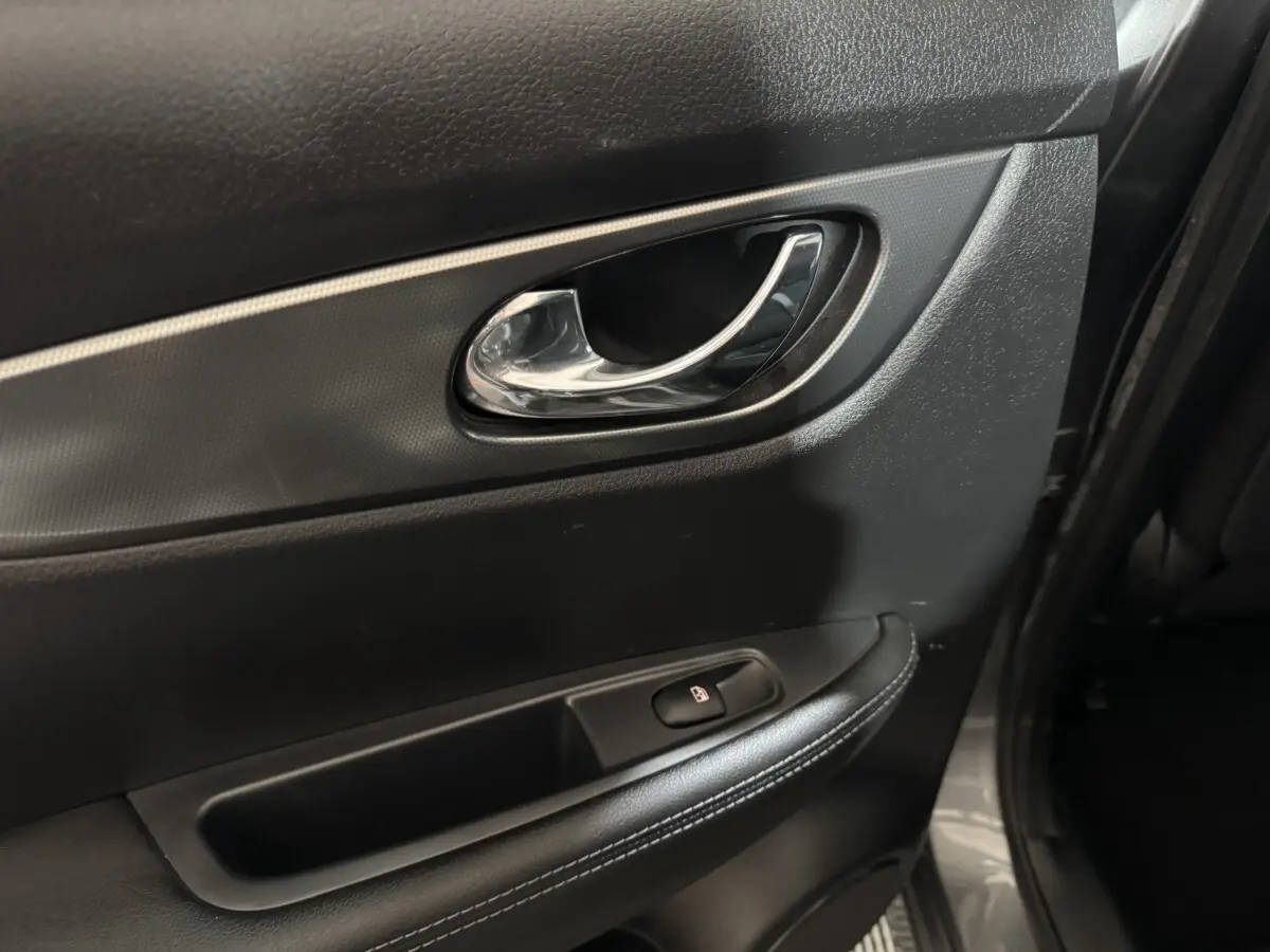 Poignée intérieure de porte arrière droite du Nissan Qashqai gris foncé, avec bouton de verrouillage et garniture noire.