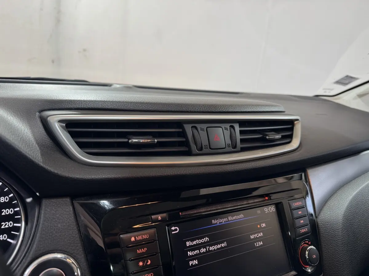 Gros plan sur la console centrale du Nissan Qashqai gris foncé, mettant en valeur l'écran tactile et les commandes.