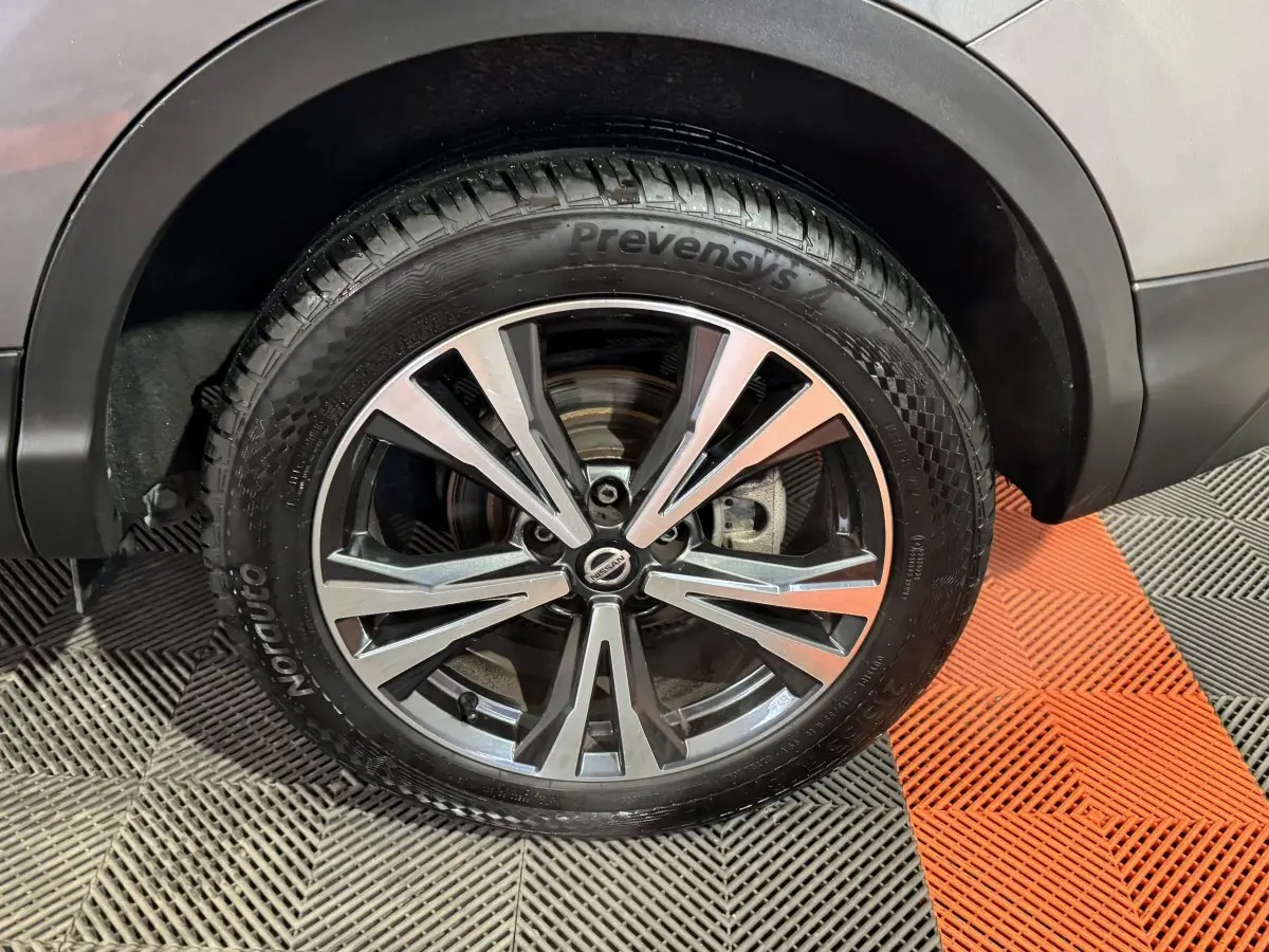 Gros plan sur la roue avant droite du Nissan Qashqai gris foncé, avec jante alliage bicolore et pneu Prevensys.