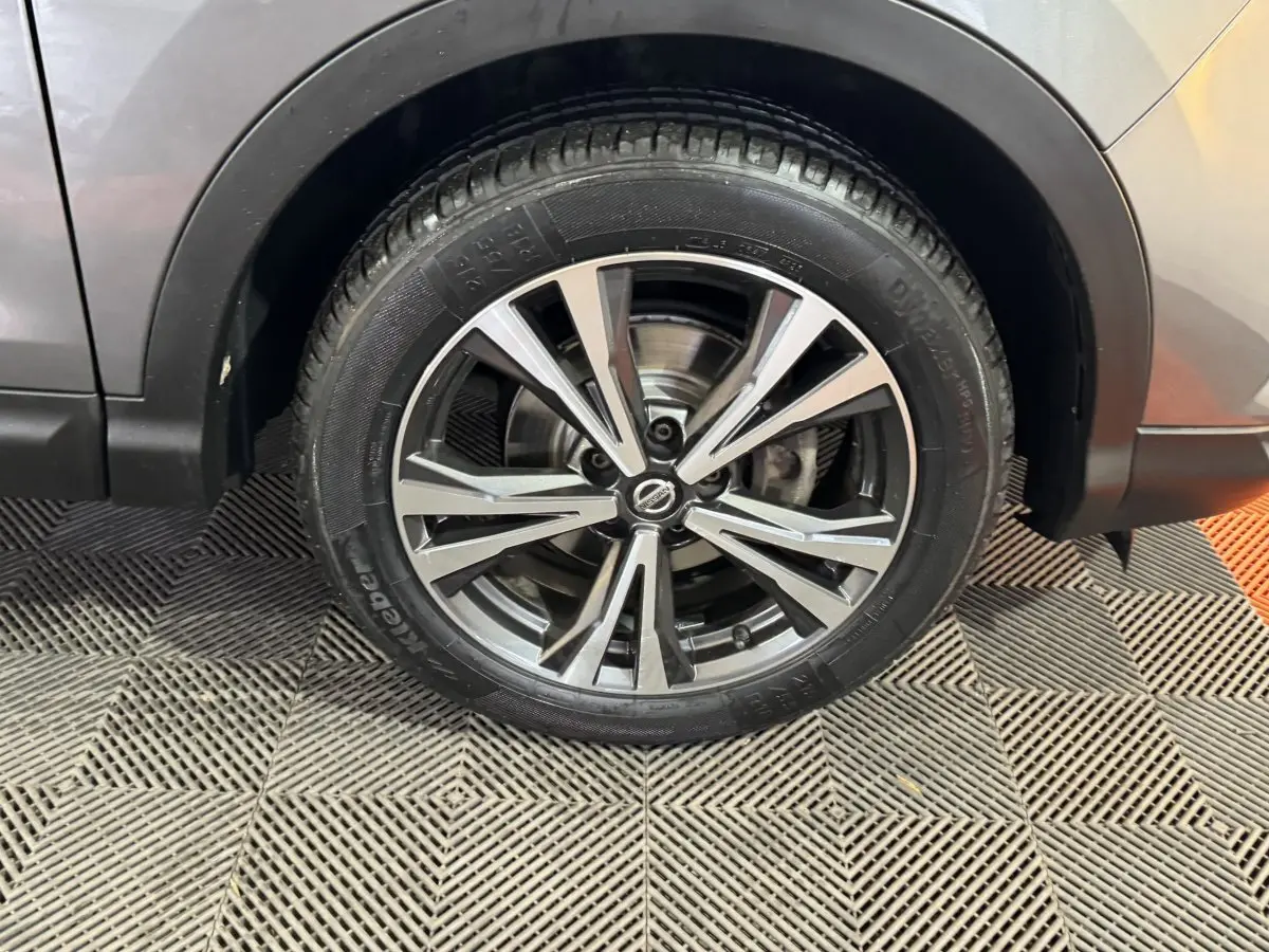 Gros plan sur la roue avant droite du Nissan Qashqai gris foncé avec jante alliage à rayons doubles.