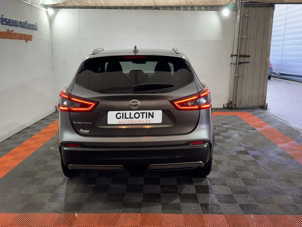 Vue arrière du Nissan Qashqai gris foncé 2019 avec feux LED allumés dans un garage aux bandes orange au sol.