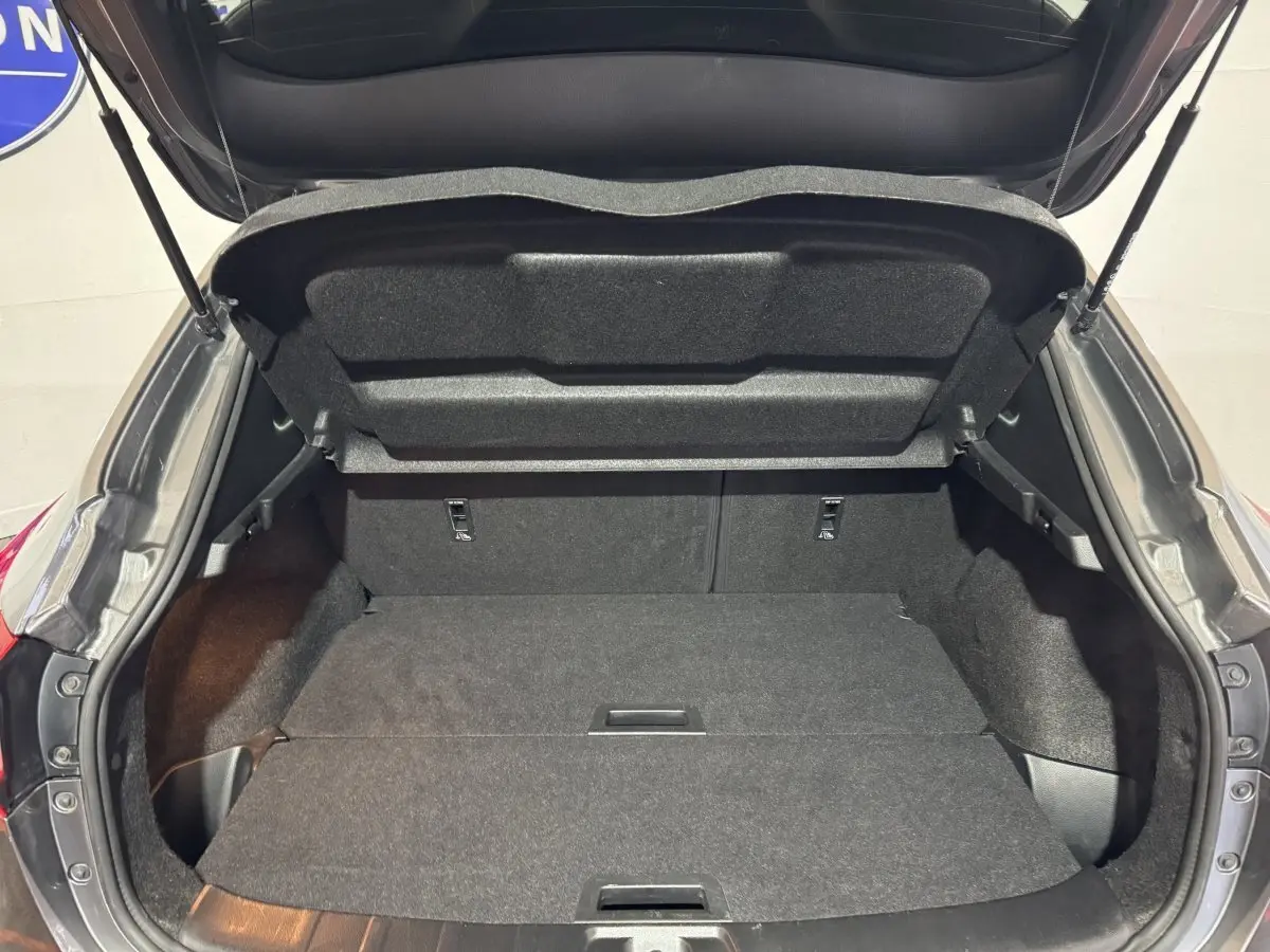 Coffre ouvert du Nissan Qashqai gris foncé, vue arrière montrant l'espace de chargement plat et spacieux.