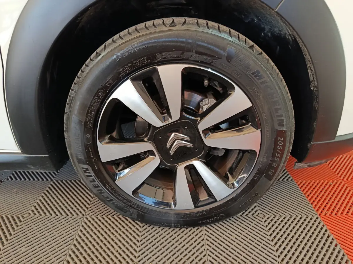 Gros plan sur la roue avant droite d'une Citroën C3 blanche, avec jante alliage bicolore et logo Citroën central.