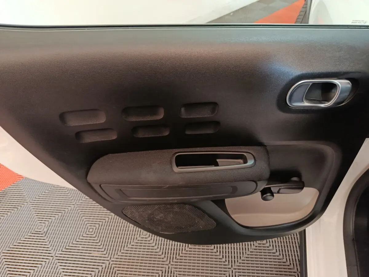 Vue intérieure sur la porte avant droite noire et blanche de la Citroën C3 avec poignée et manivelle de vitre.