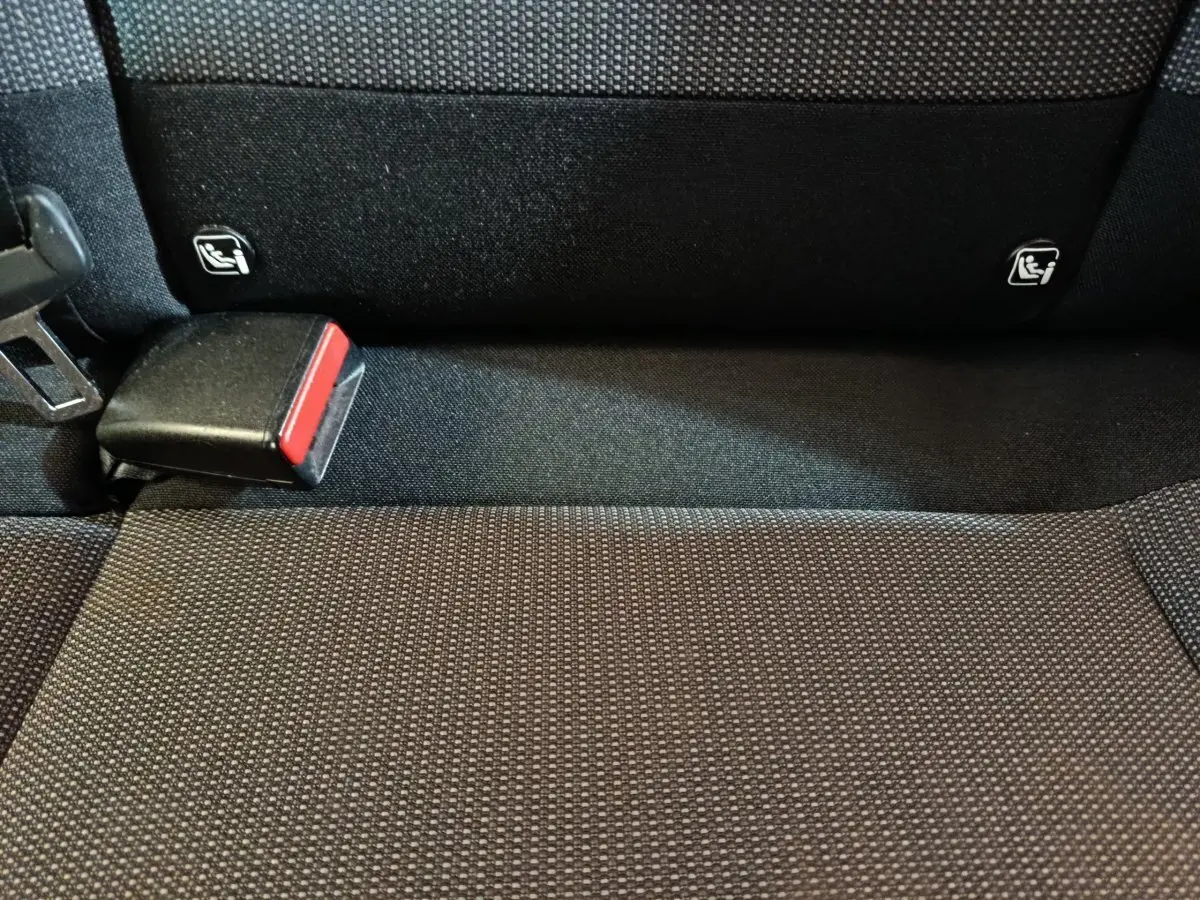 Gros plan sur la banquette arrière noire de la Citroën C3 avec attaches Isofix et boucle de ceinture rouge visible.
