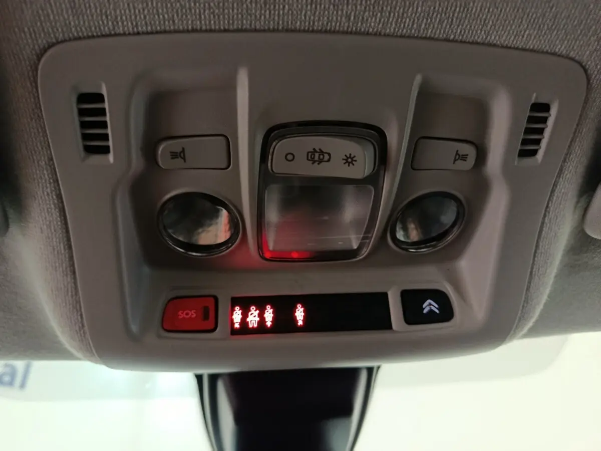 Vue en gros plan du plafonnier intérieur gris avec commandes d’éclairage et boutons SOS de la Citroën C3 blanche.