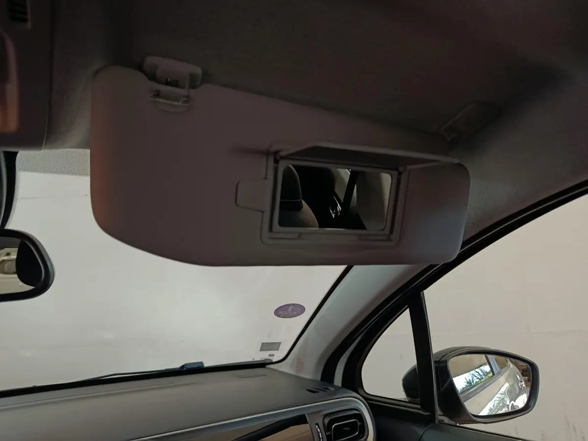 Intérieur de la Citroën C3 blanche, vue côté passager avec pare-soleil et miroir de courtoisie déployé.