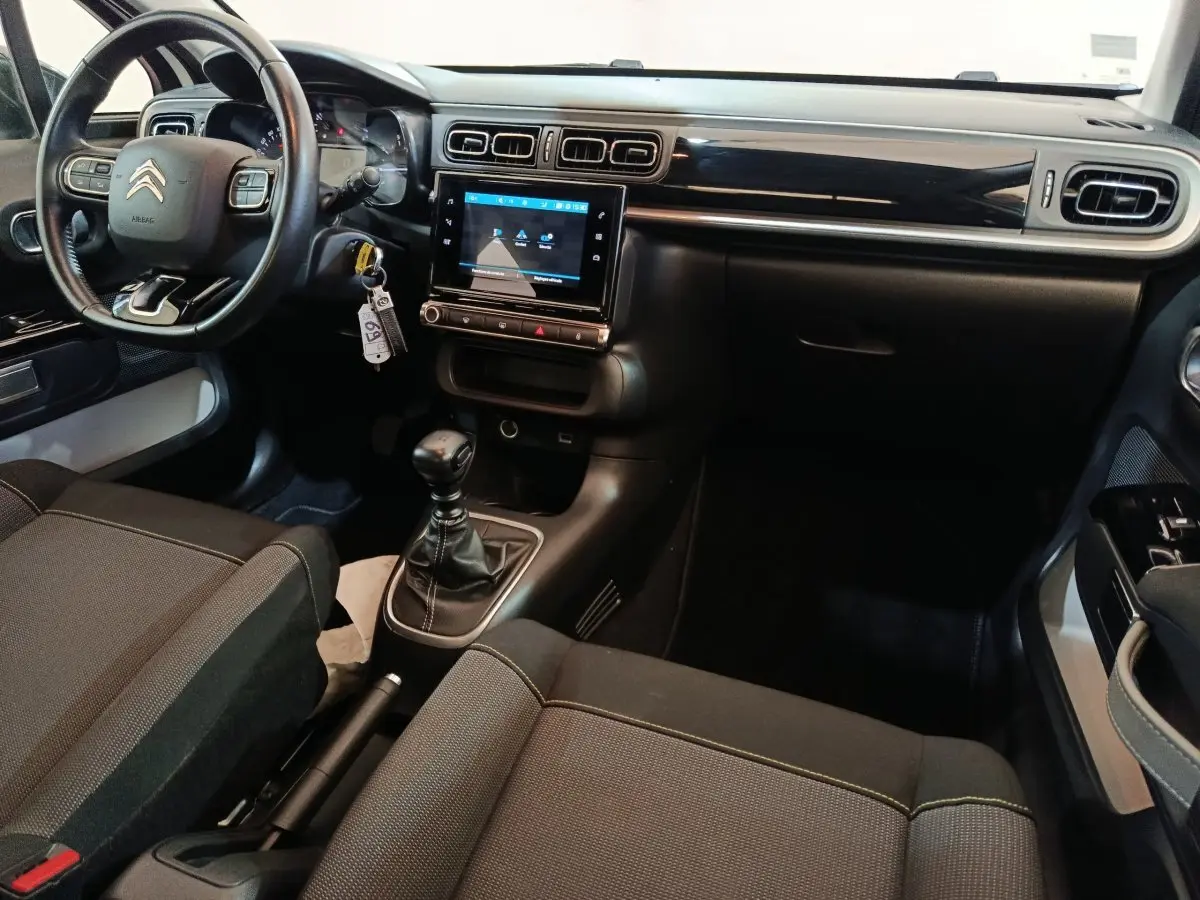 Vue intérieure côté conducteur de la Citroën C3 2021, tableau de bord noir avec écran tactile central et volant cuir.