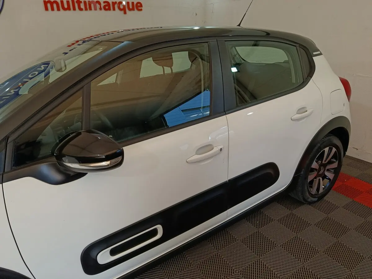 Vue latérale droite d'une Citroën C3 blanche avec protections noires sur les portes et rétroviseur noir brillant.