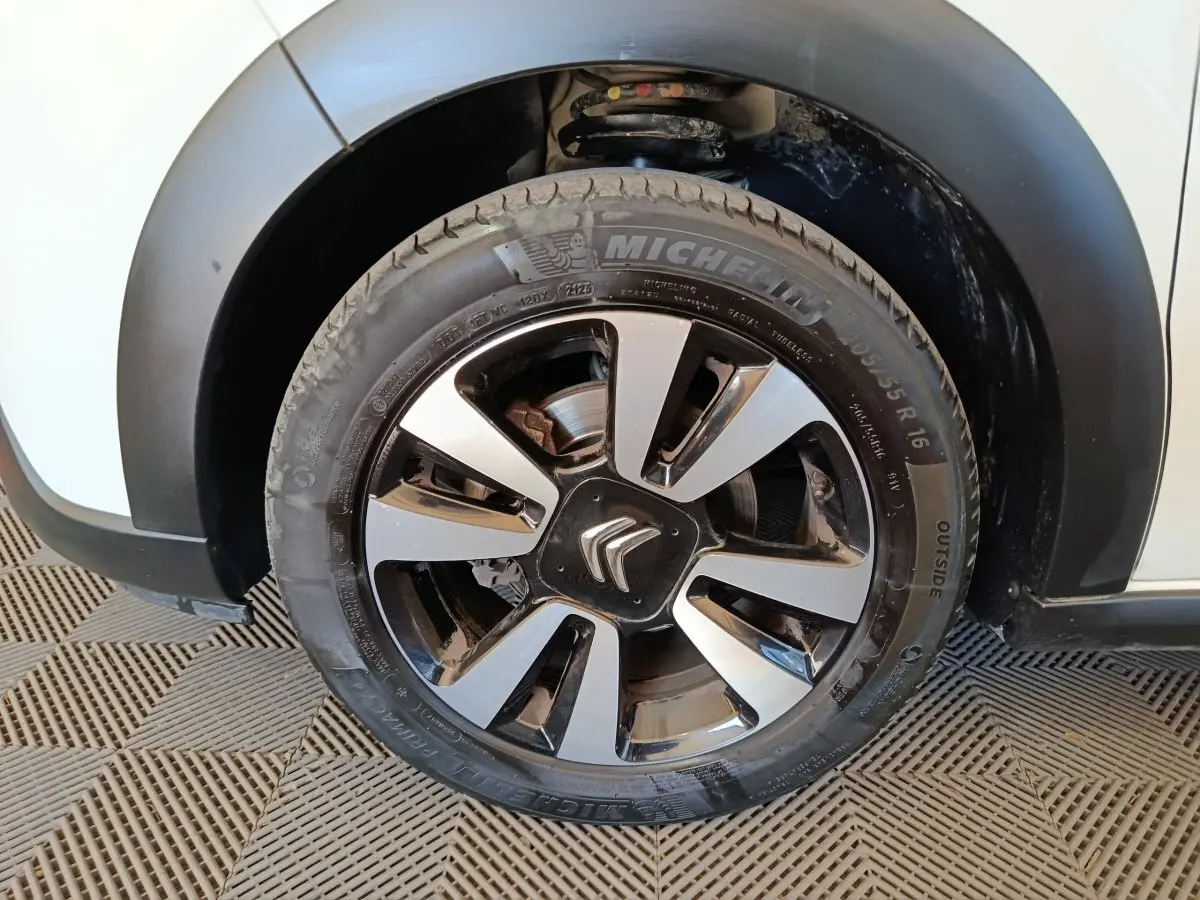 Gros plan sur la roue avant gauche d'une Citroën C3 blanche, jante alliage bicolore avec logo Citroën central.