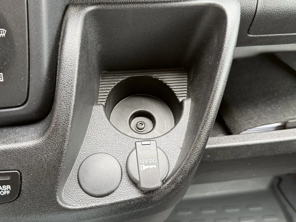 Gros plan sur la prise 12V et rangement noir dans l’habitacle du Peugeot Boxer Fourgon blanc, côté conducteur.