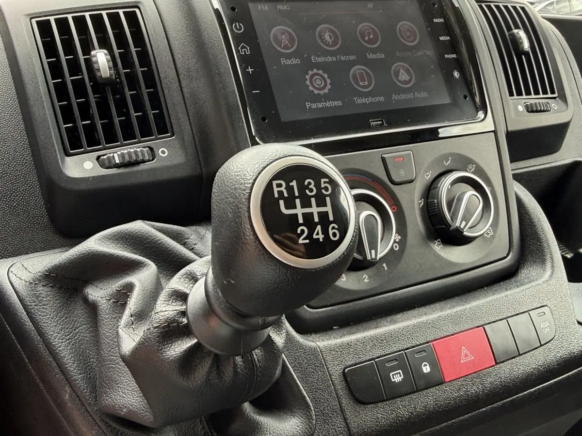 Gros plan sur levier de vitesse manuel et commandes de climatisation du tableau de bord du Peugeot Boxer Fourgon blanc 2023.