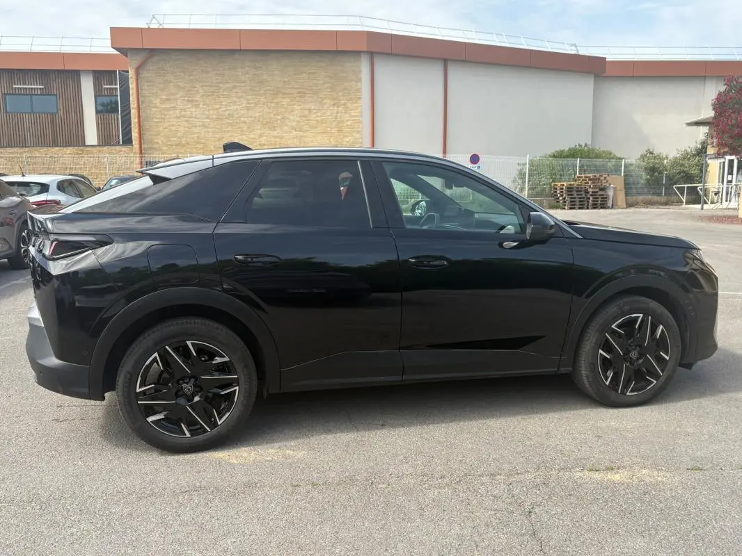 Profil côté gauche du Peugeot 3008 Hybrid noir de 2025 avec jantes alliage noires de 19 pouces, en extérieur sur parking.
