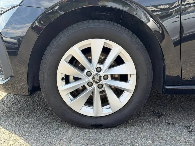 Gros plan sur la roue avant gauche d'une Skoda Scala noire Magic nacré avec jante alu à dix branches.