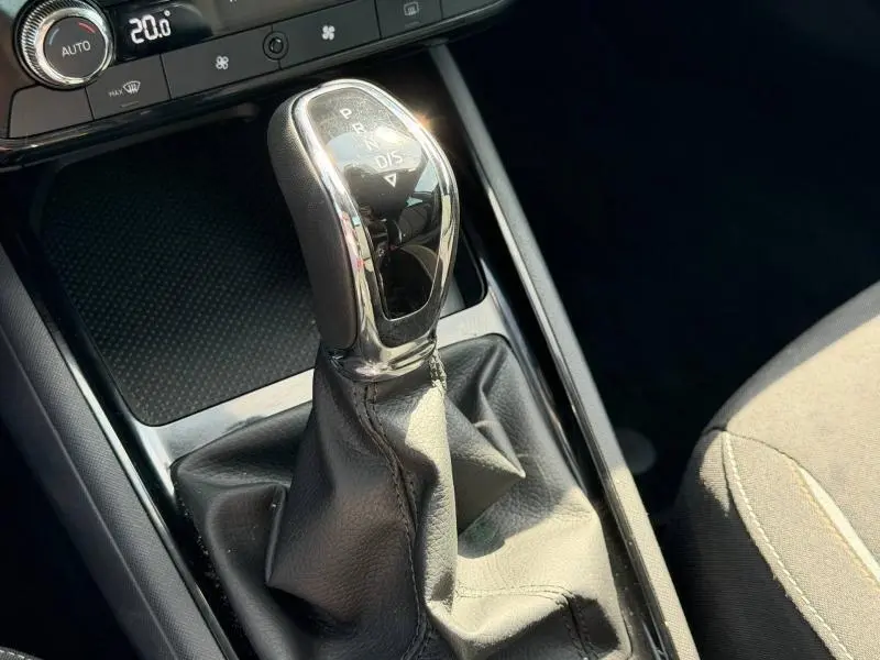Gros plan sur le levier de vitesse automatique en cuir noir et chrome de la Skoda Scala 2025, intérieur tissu gris.