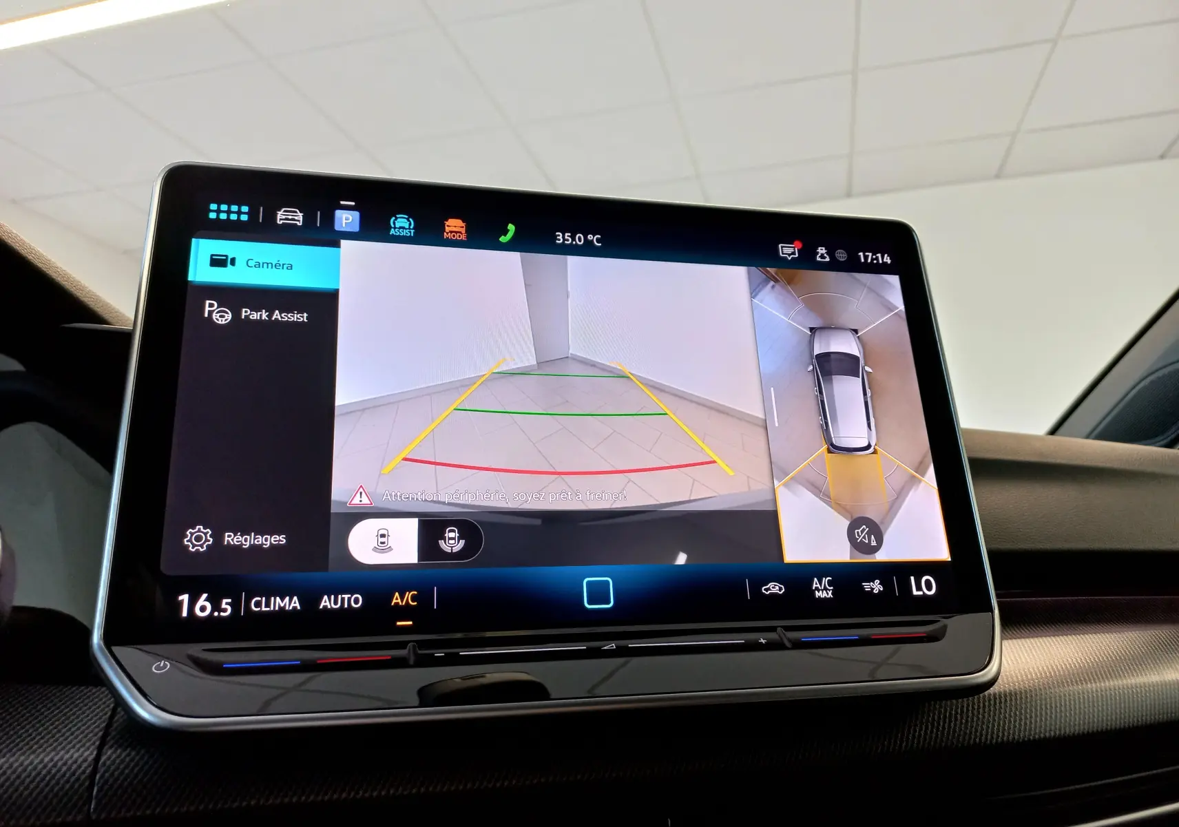 Écran tactile intérieur affichant la caméra 360° avec vue arrière et vue aérienne de la Volkswagen Golf gris dauphin.