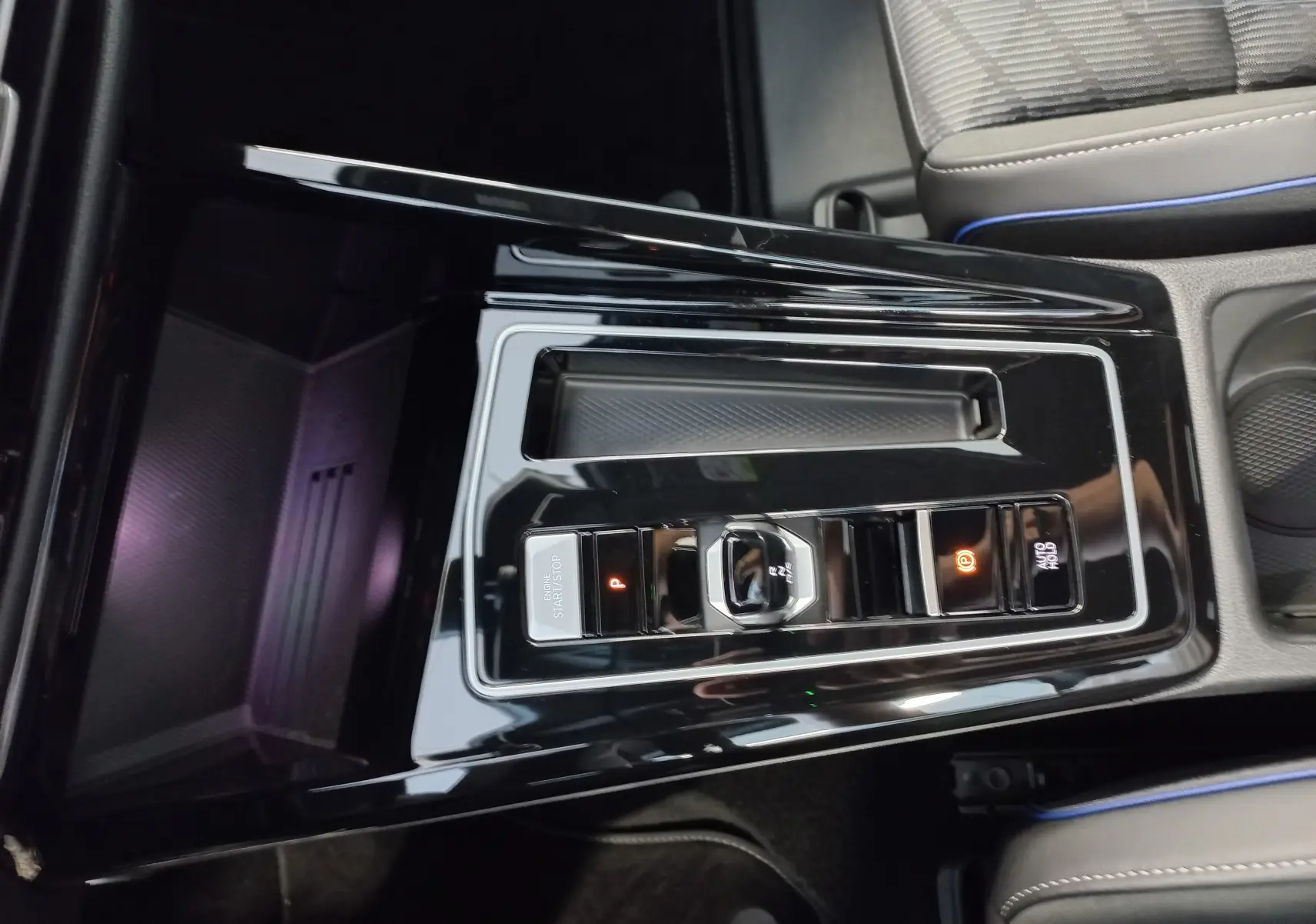 Vue rapprochée de la console centrale noire brillante de la Volkswagen Golf 1.5 eTSI R-Line avec commandes électroniques et sièges gris.