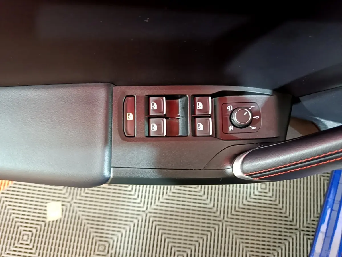 Gros plan sur les commandes de lève-vitres et réglage des rétroviseurs côté conducteur d’une SEAT Leon bleu 2021.