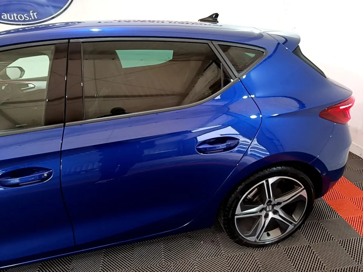 Vue latérale droite d'une SEAT Leon bleu électrique, mettant en valeur les jantes alliage et les vitres teintées.