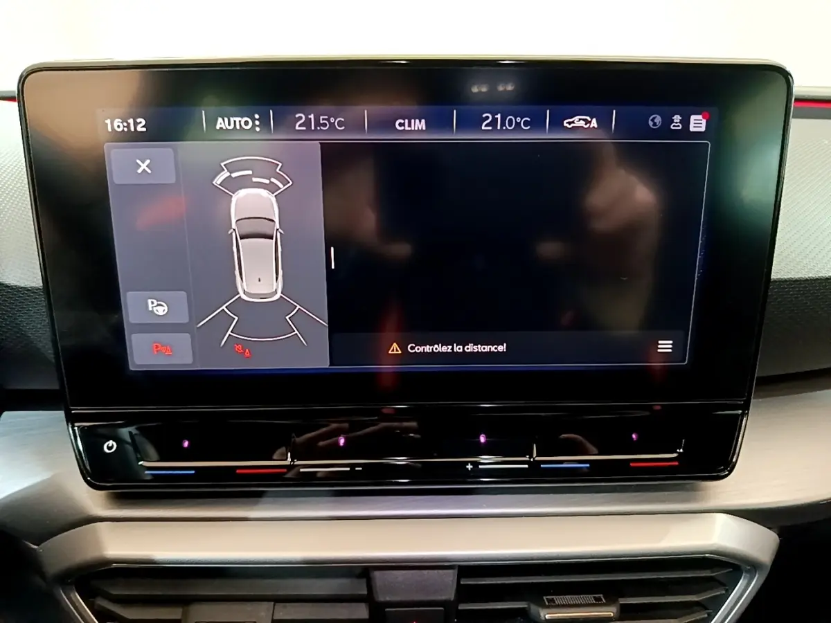 Écran tactile central du tableau de bord du SEAT Leon 1.5 eTSI bleu, affichant l'aide au stationnement.