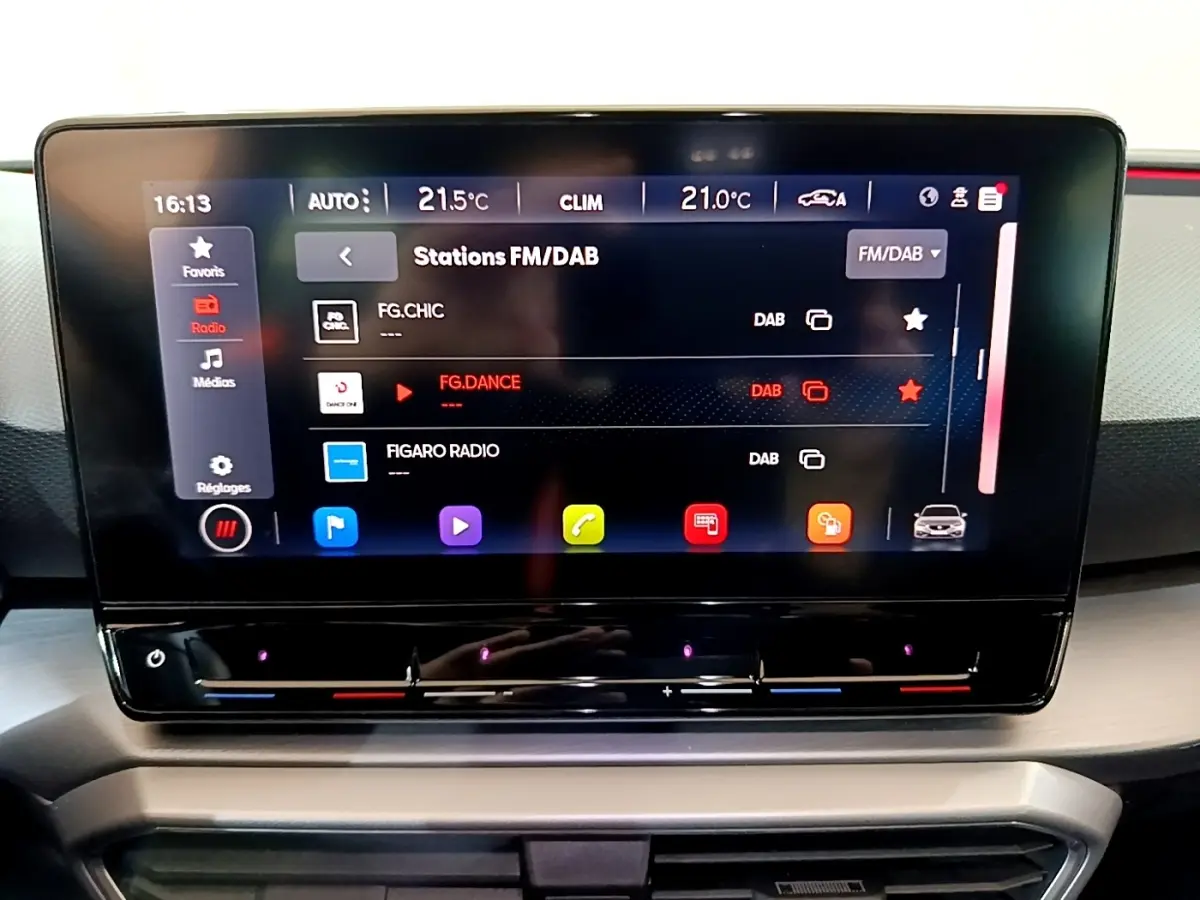 Écran tactile central du tableau de bord du SEAT Leon 1.5 eTSI bleu, affichant les stations radio FM/DAB.