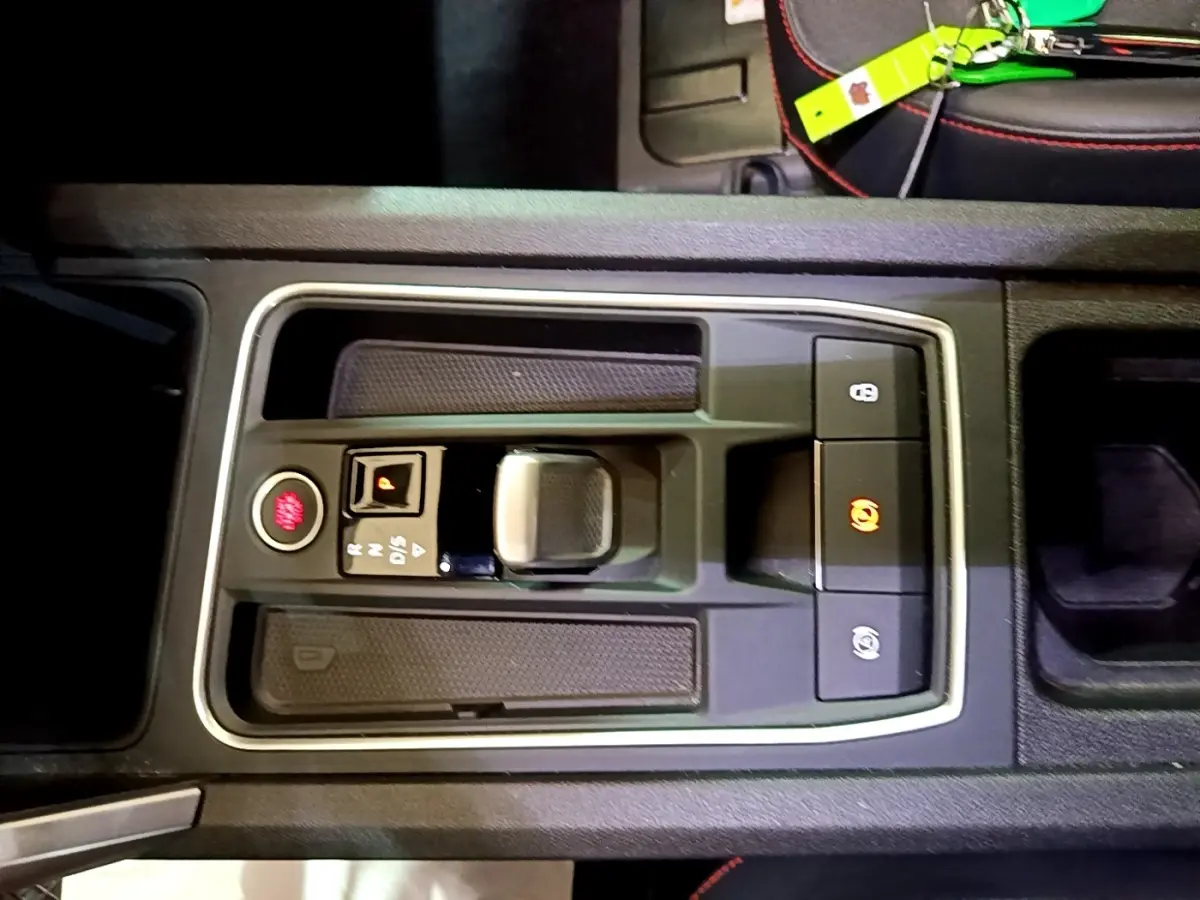 Vue rapprochée de la console centrale noire du SEAT Leon 1.5 eTSI avec levier de vitesse automatique et boutons de frein à main.