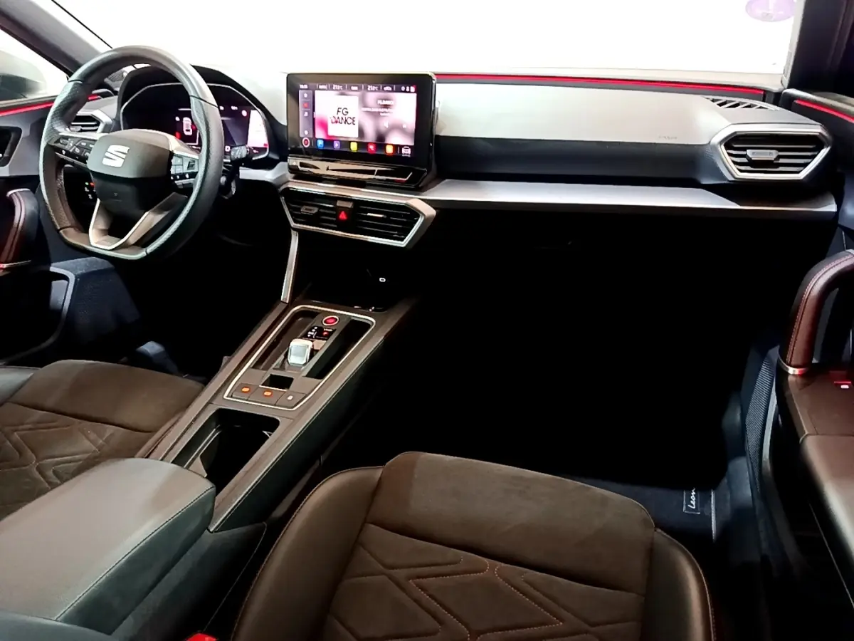 Vue intérieure côté conducteur du tableau de bord et console centrale du SEAT Leon bleu avec écran tactile et volant multifonctions.