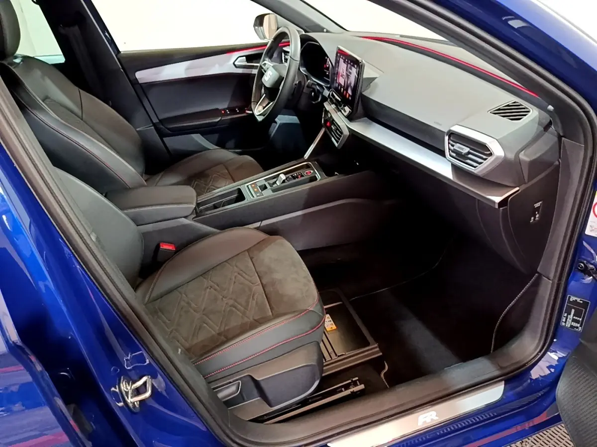 Intérieur de la SEAT Leon bleu, vue côté droit, avec sièges noirs et tableau de bord moderne à écran tactile.