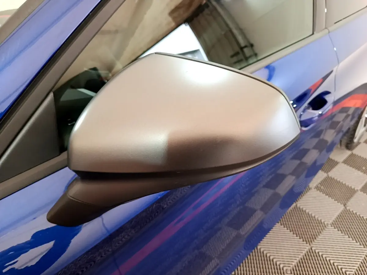 Rétroviseur côté gauche gris mat sur SEAT Leon bleu, vue rapprochée du profil avant droit.