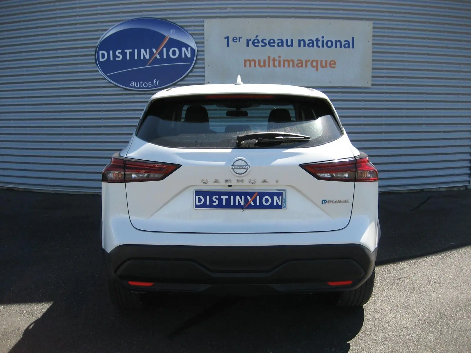 Vue arrière d'un Nissan Qashqai blanc nacré 2024 avec logo e-POWER et plaque Distinxion visible.