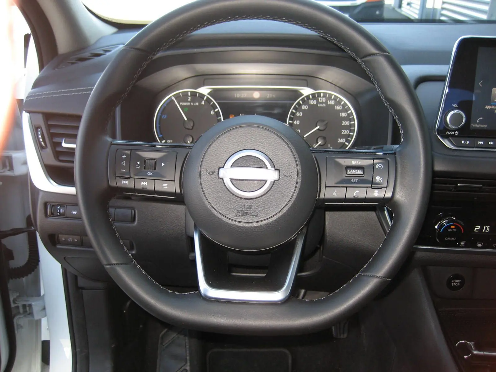 Vue centrée sur le volant noir du Nissan Qashqai blanc nacré 2024, avec tableau de bord et commandes visibles.