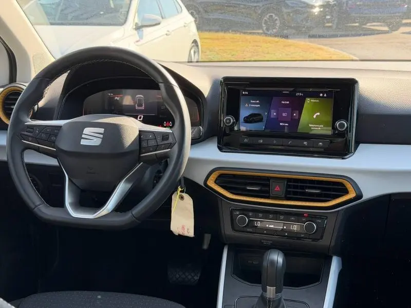 Vue intérieure avant du tableau de bord du SEAT Arona blanc avec volant cuir multifonction et écran tactile central.