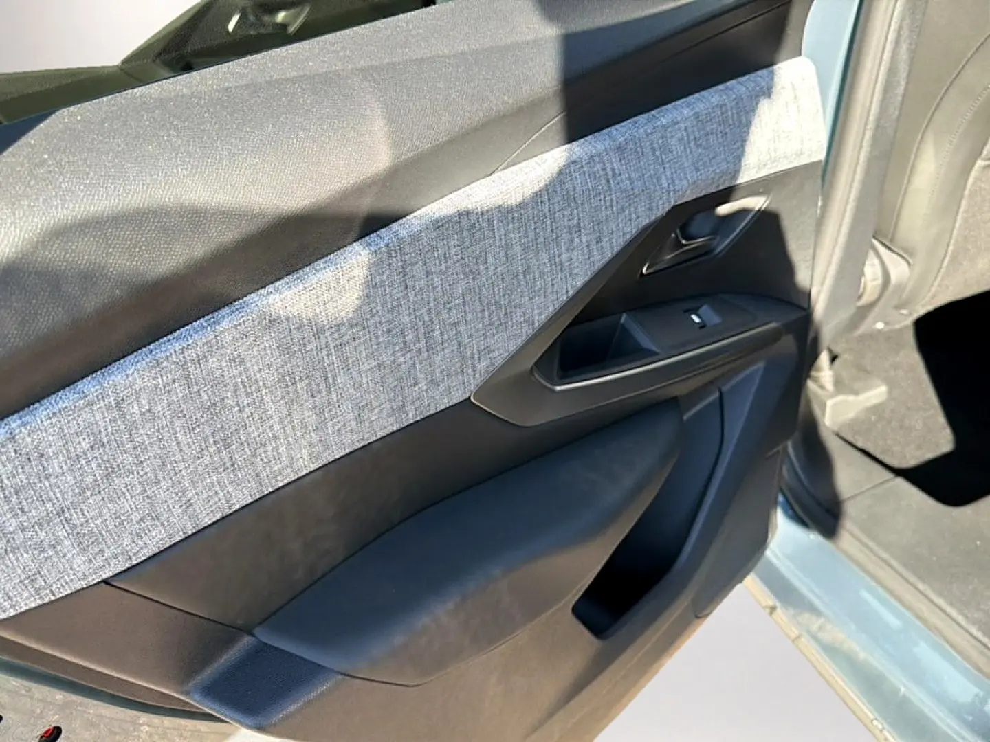 Vue rapprochée de la porte avant gauche bleu clair du Peugeot 3008 1.2 hybrid 145 allure avec habillage tissu gris.