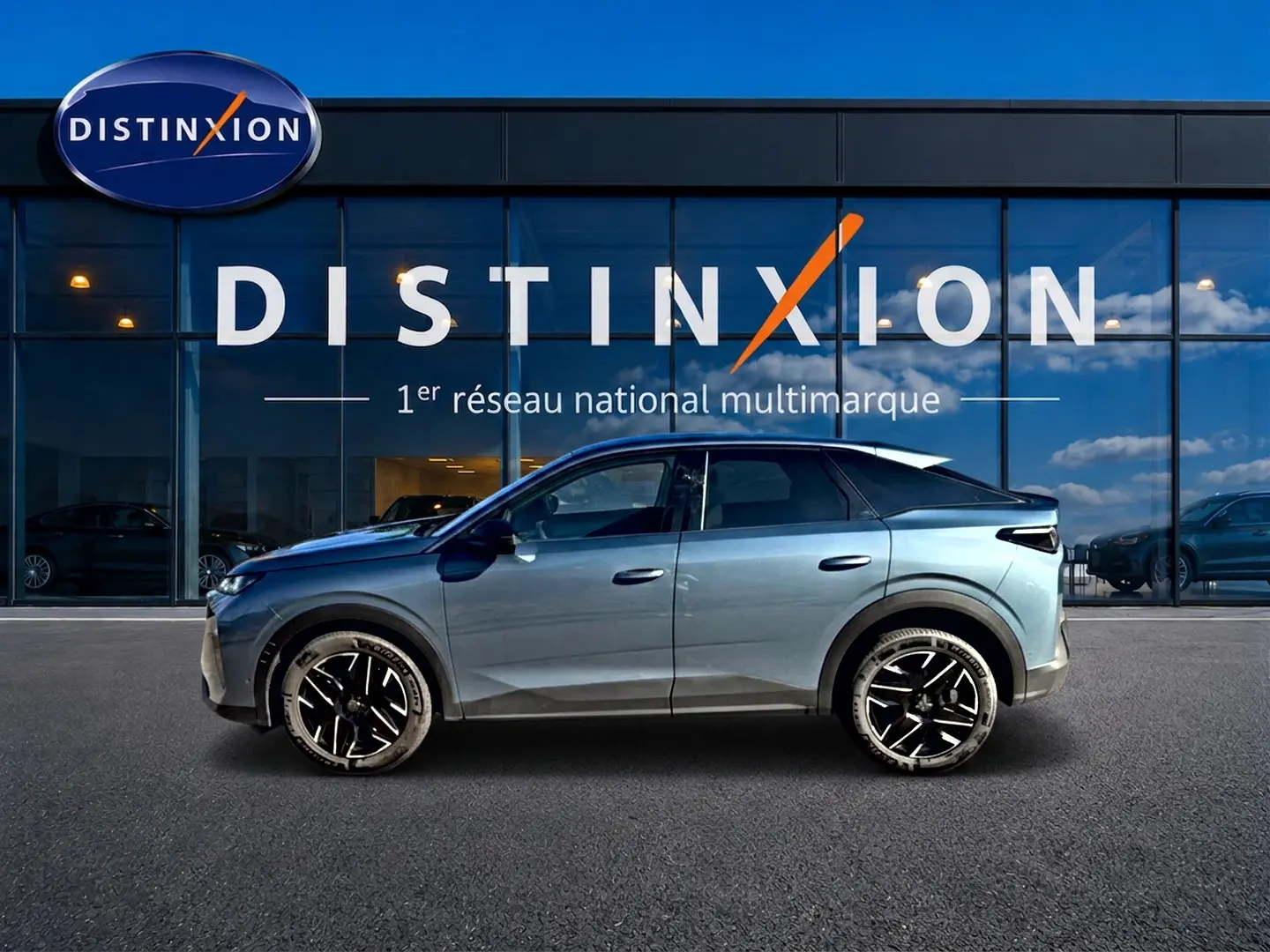 Vue de profil côté gauche du Peugeot 3008 hybride 2025 bleu avec jantes alliage noires devant une vitrine Distinxion.