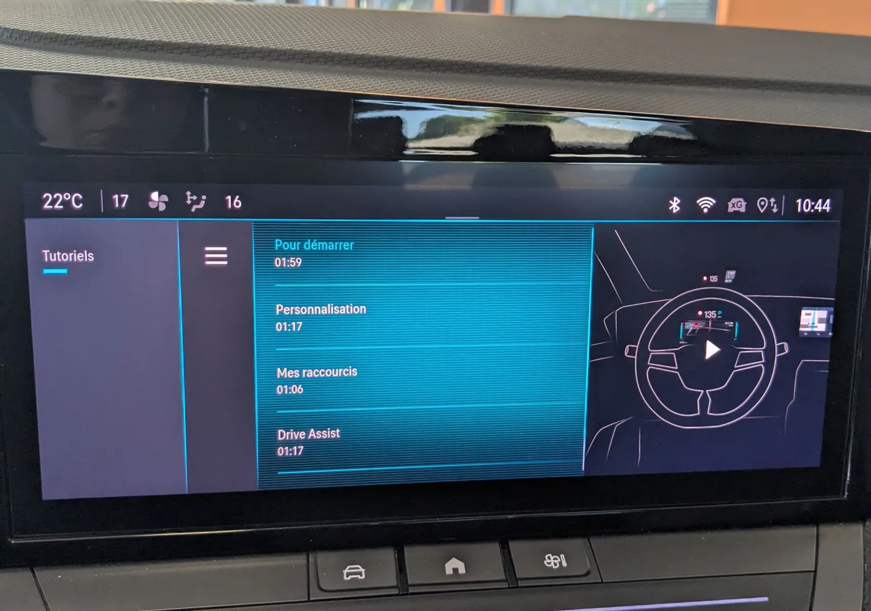 Écran tactile central de l’Opel Astra 2022 affichant le menu tutoriels et commandes climatisation en intérieur noir.