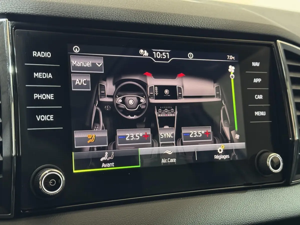 Écran tactile central affichant la climatisation bi-zone et vue stylisée du tableau de bord du Skoda Karoq blanc.