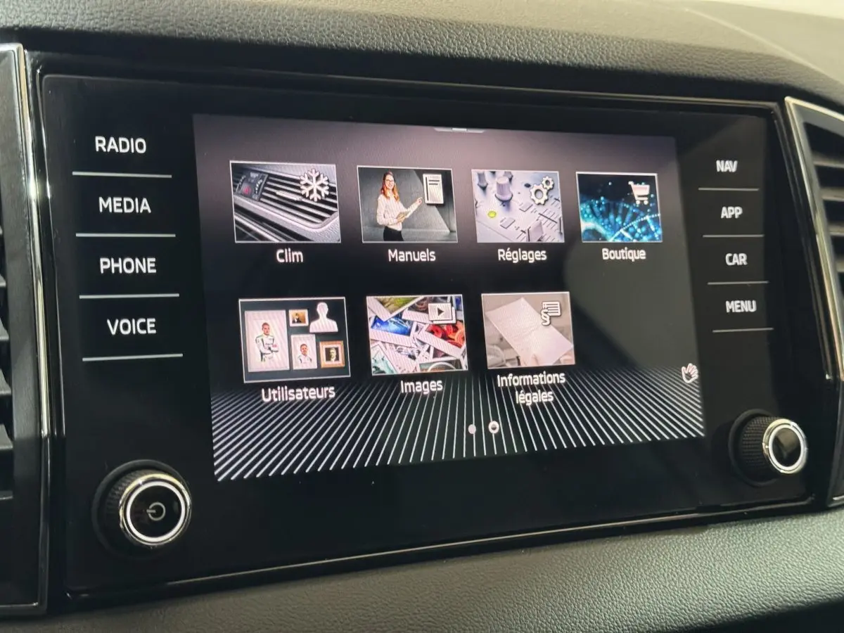 Écran tactile central du Skoda Karoq 1.5 TSI blanc, affichant les menus climatisation, manuels et réglages.
