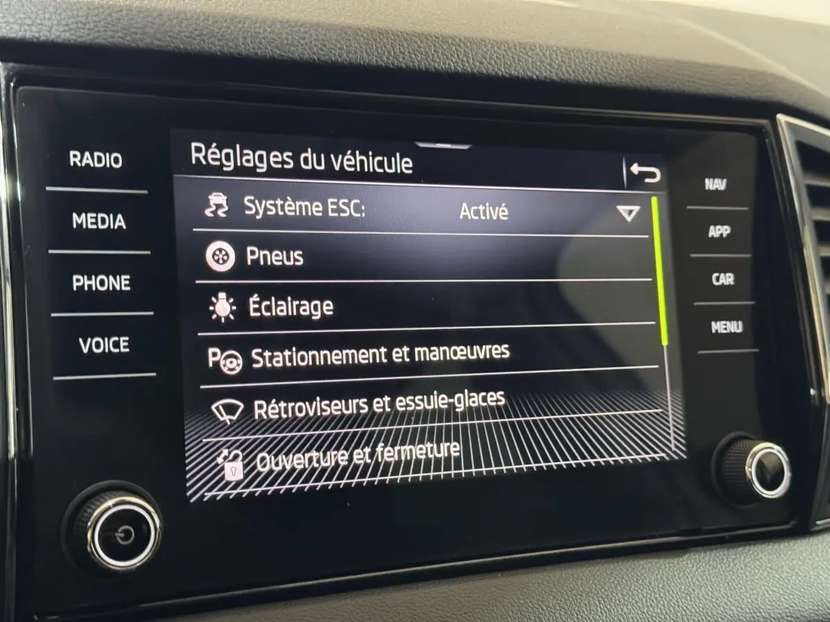 Écran tactile central affichant les réglages du véhicule dans un Skoda Karoq blanc, vue rapprochée intérieure.
