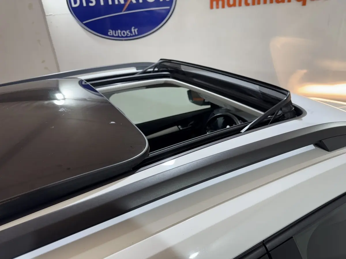 Toit ouvrant panoramique ouvert sur le côté gauche d'un Skoda Karoq blanc, rails de toit gris visibles.