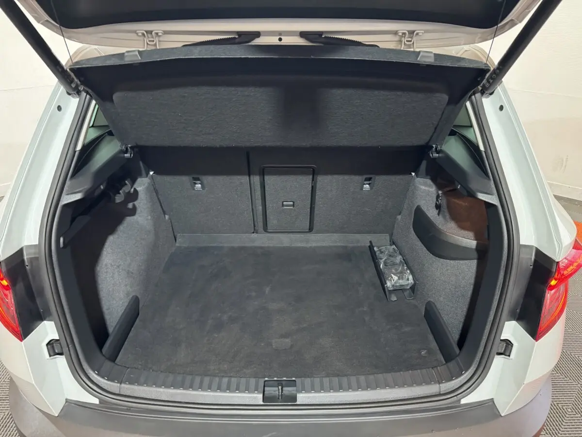 Coffre ouvert vu de l'arrière d'un Skoda Karoq blanc 2021, espace de chargement propre et spacieux.