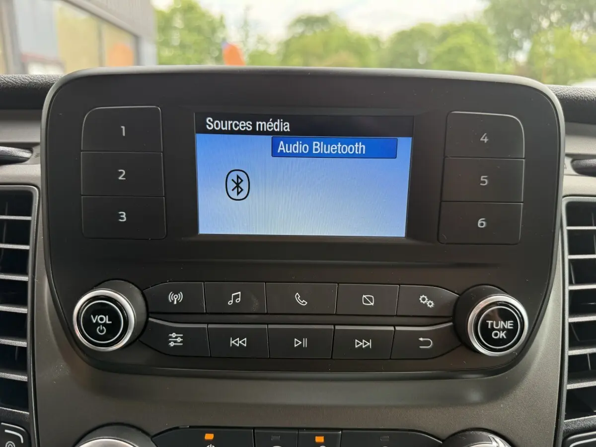 Écran central du Ford Transit Fourgon 2024 affichant la source audio Bluetooth, avec commandes et boutons autour.