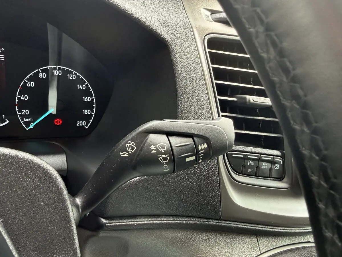 Vue intérieure rapprochée du levier d'essuie-glace et des commandes près de la ventilation du Ford Transit Fourgon 2024.