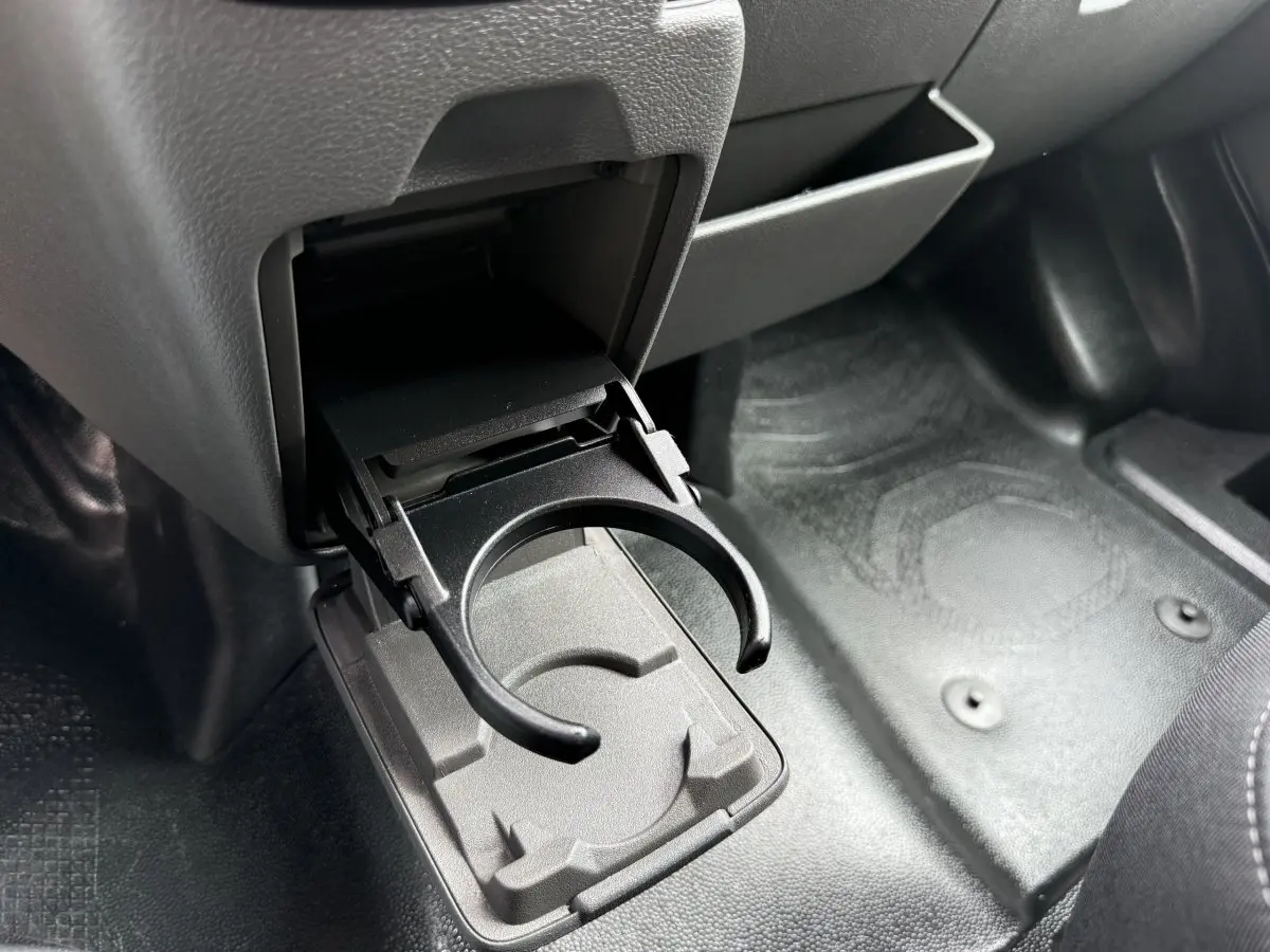 Gros plan sur le porte-gobelet déplié côté passager dans l'habitacle gris foncé du Ford Transit Fourgon blanc.
