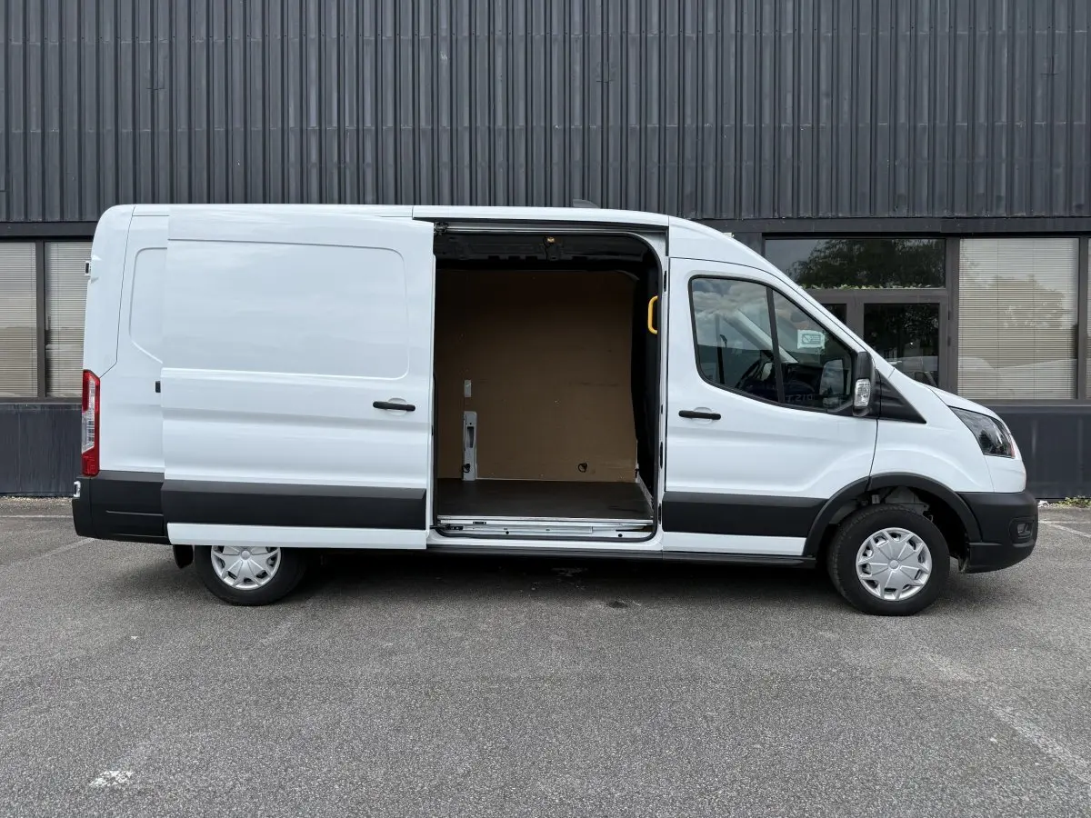 Ford Transit Fourgon blanc vu de profil droit avec porte latérale coulissante ouverte montrant l’espace de chargement.